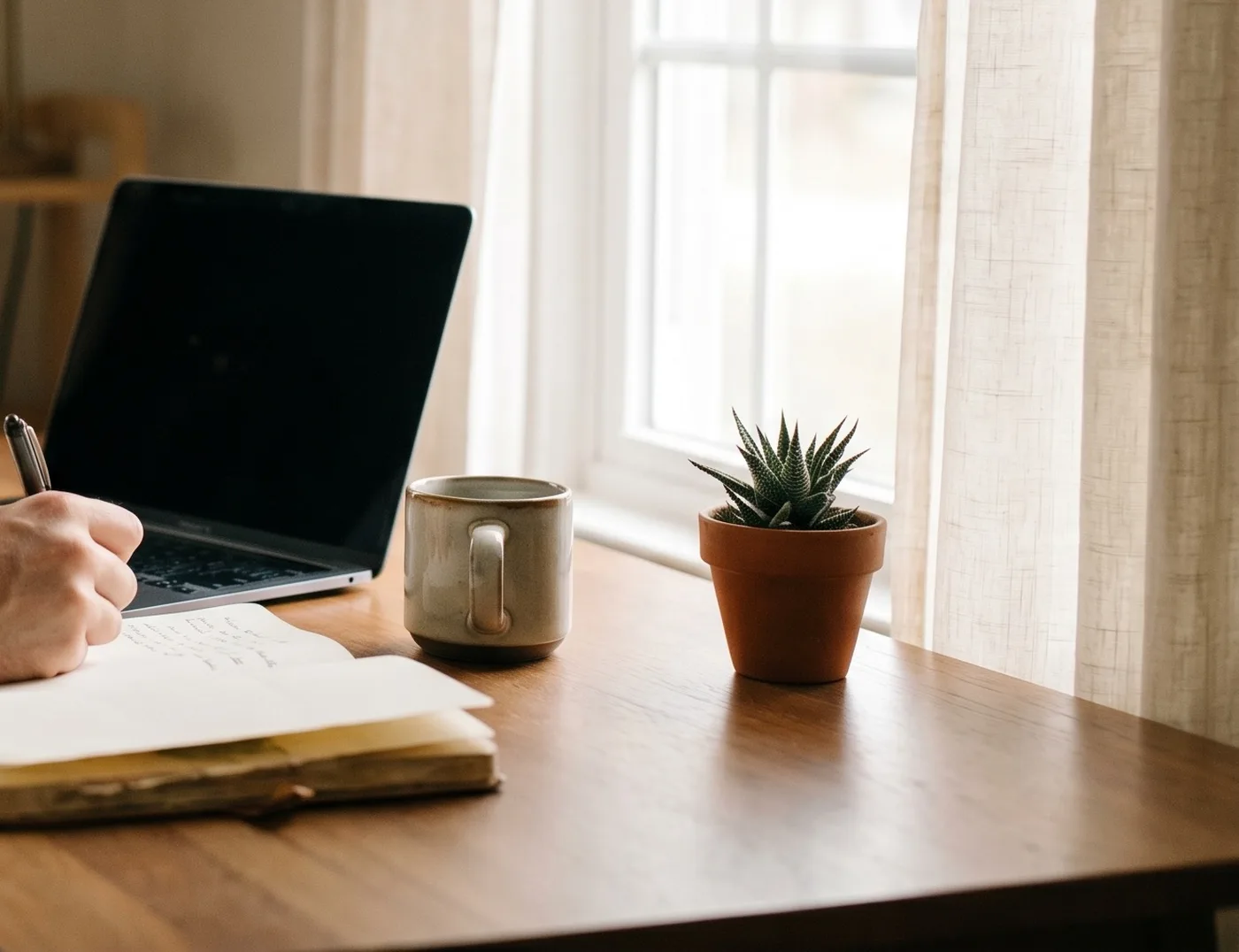 Ein Schreibtisch mit Laptop, Notizbuch und einer Tasse Kaffee