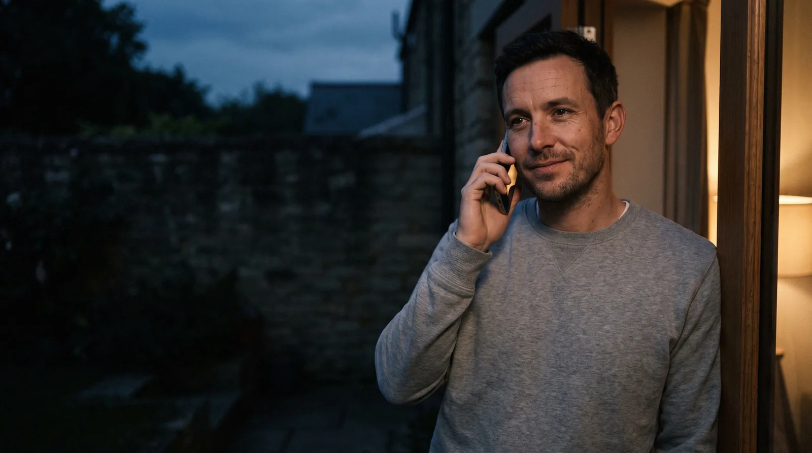 A home-services pro taking a call outside a house